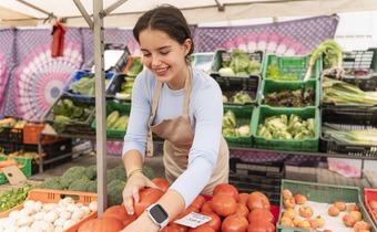 woman grabbing tomatoes at farmers market stall