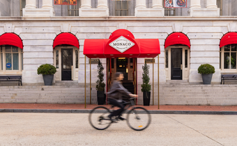 man on bicycle riding past Kimpton Monaco DC